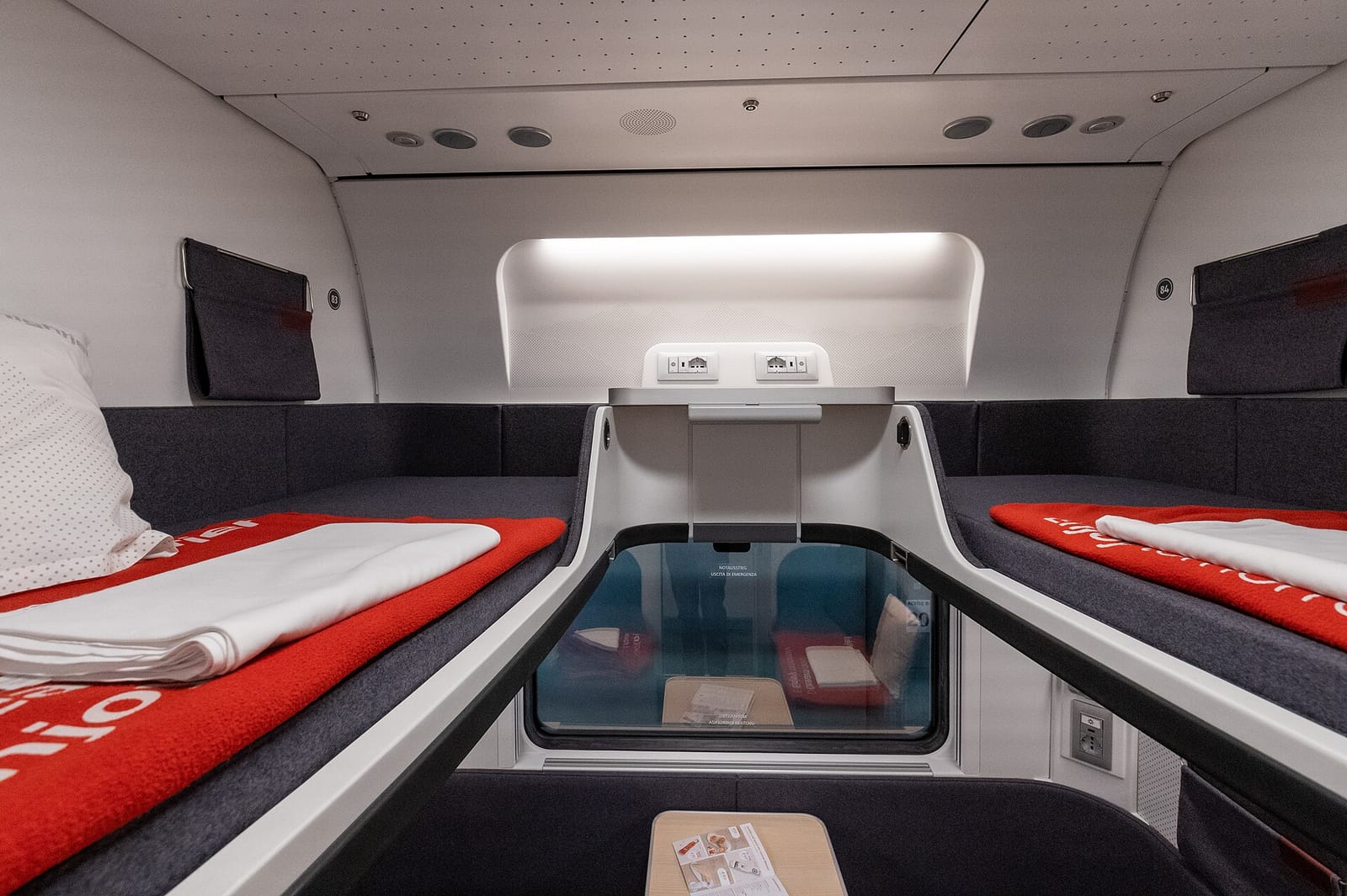 A new-generation Nightjet couchette compartment with a made-up berth on each side and the window between them.