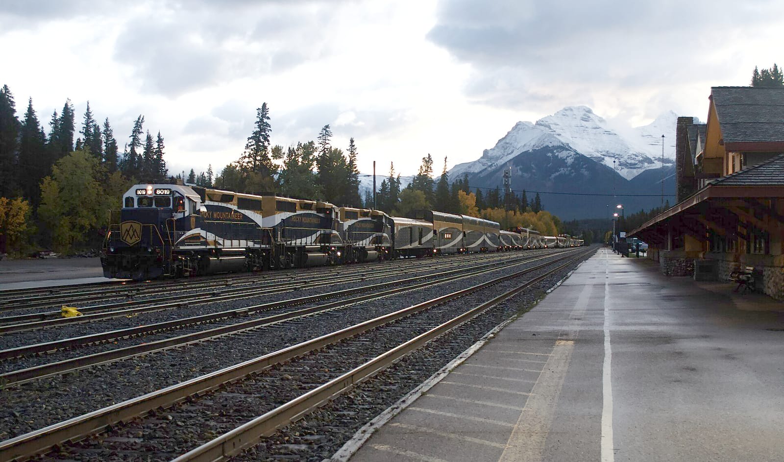 The Rocky Mountaineer train at Banff station at dawn in October 2024, with a snow-capped mountain behind.